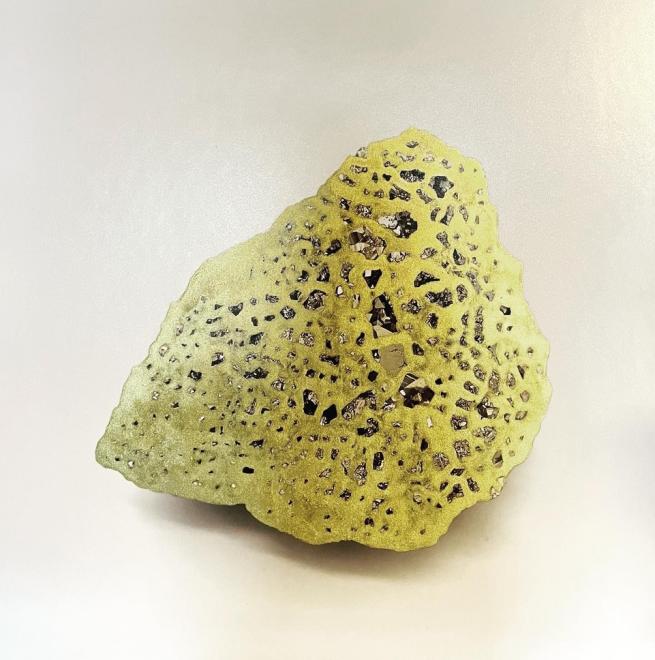 Artwork by Lorna Johnson that shows a lack and white photo of a rock containing fools gold, this has been drawn on with an elaborate net of gold pen that covers all contours of the rock. 