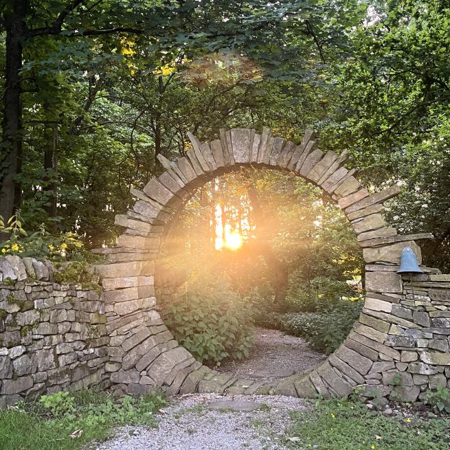 stone circle with sun behind it coming through the trees