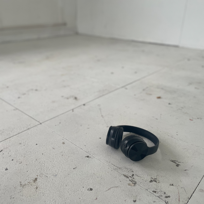 A pair of black over ear headphones lie on a white floor