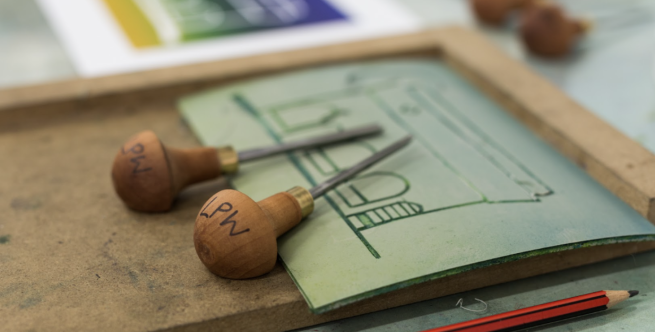 Linocut tools and a piece of lino being prepared for printing