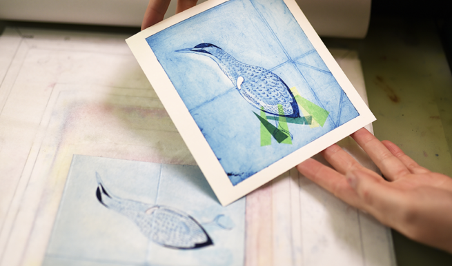 A printed image of a bird in shades of blue being revealed after being printed from a piece of TetraPak
