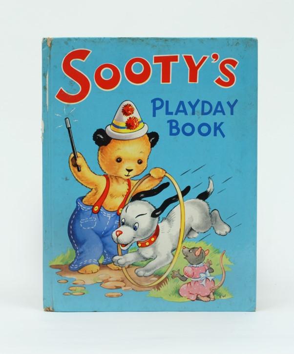 A book with a picture of a bear and a dog (Sooty and Sweep). Sooty is wearing a clown hat and Sweep is jumping through a hoop.