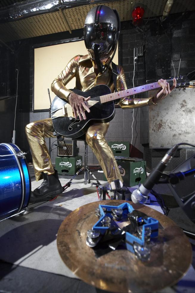 Portrait of Bob playing live in a gold jumpsuit 