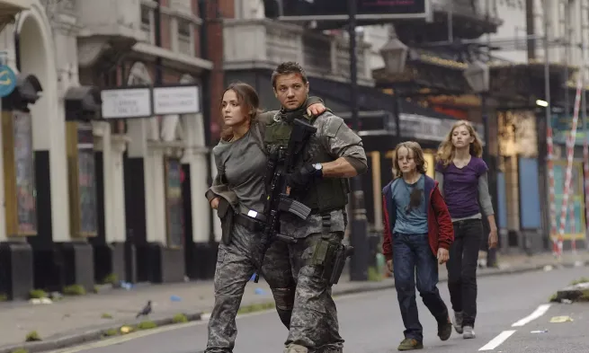 A man and a woman wearing military gear, walk through an empty street, ahead of two children.