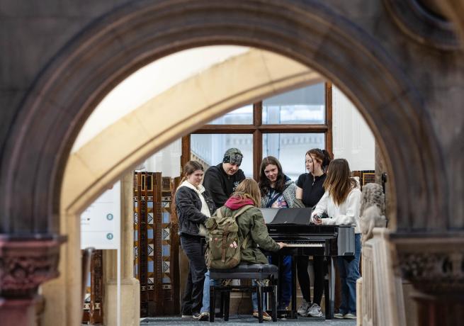 Group stood round piano in Central building 
