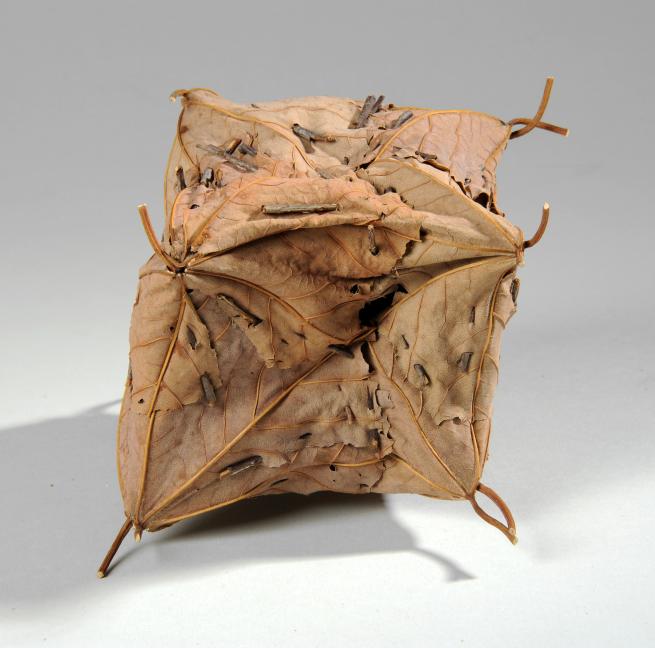 A sculpture made from several brown leaves stuck together to make a cube shape