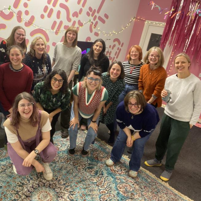 Members of Cosy Choir smiling at the camera in a colourful room
