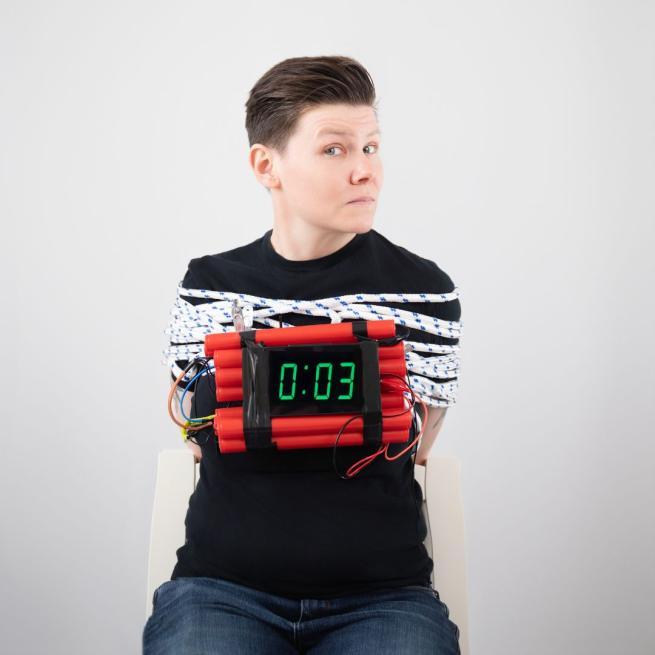 Grace Petrie tied up in rope with a bomb strapped to her. The countdown has three seconds to go.