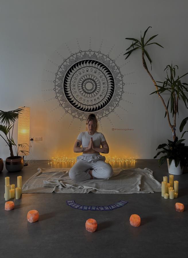 Yoga teacher Olivia sitting crossed legged with her hands in prayer pose