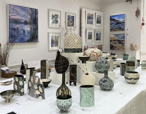 Photo taken at last year’s Open Studios showing a central display of ceramics and artworks around the walls. 