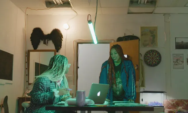 Two people talking over a laptop