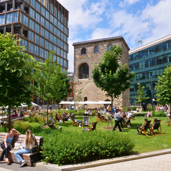People relaxing outside, visiting a market and enjoying greenery by offices in the city.