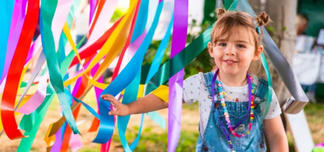 A child playing in some colourful ribbons