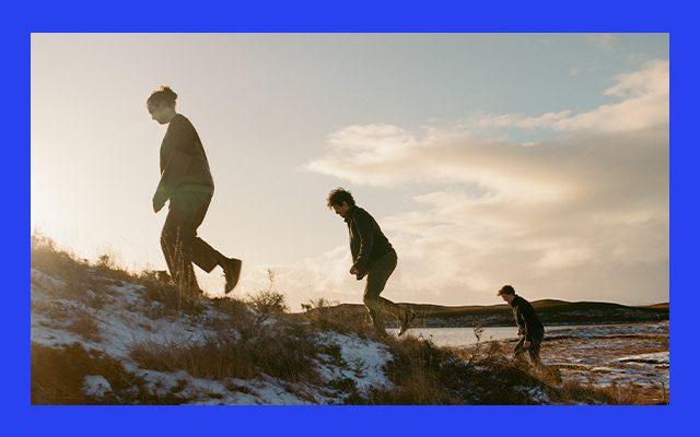 Three men walking up a snowy moorland hill