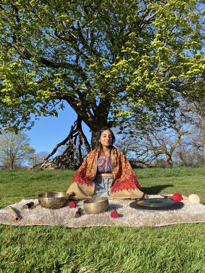 Neeta Sarl sitting beneath a tree with a selection of sound healing instruments