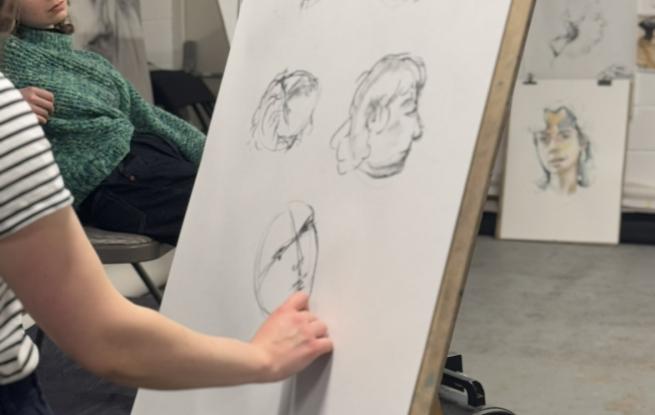 An artist stood at an easel drawing sketches of the life models face
