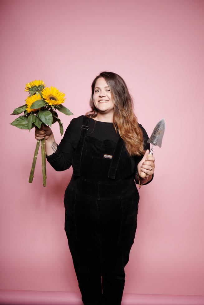 person holding a bunch of sunflowers and a trowel