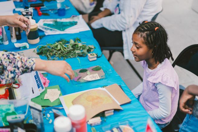 A child uses natural materials to make leaf prints in the Roxby Community Garden, Leeds.