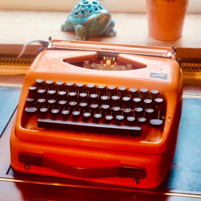 An orange typewriter sat on a desk