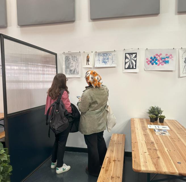 Two exhibition attendees viewing artwork on a wall