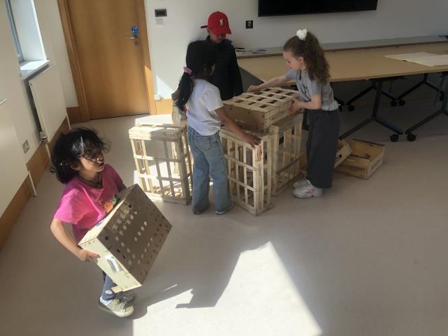 Children at a creative workshop moving and stacking wooden crates