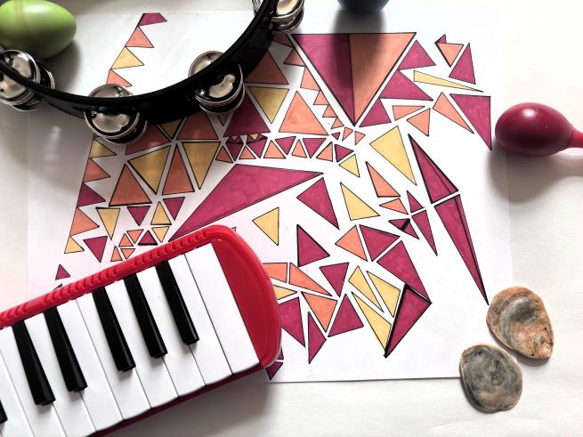  A sheet of paper with abstract, coloured triangles is surrounded by musical instruments.