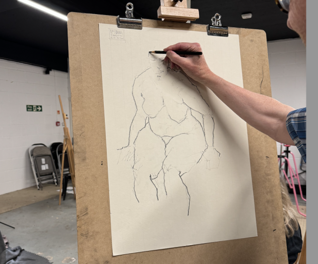 POV of an artist stood at an easel drawing a female life model