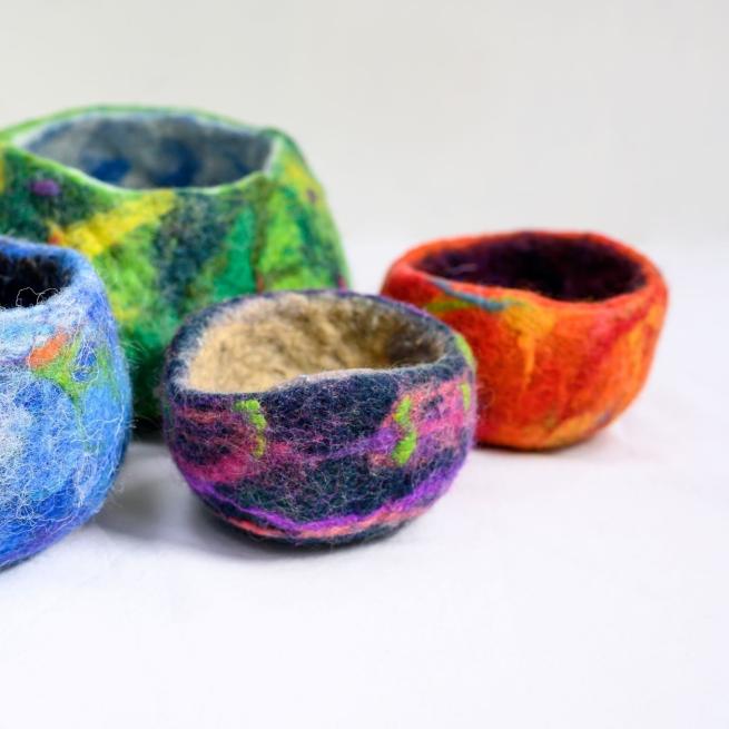A collection of colourful felted bowls against a white backdrop