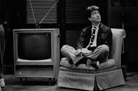 Young David Lynch sitting on a sofa with a TV in the background