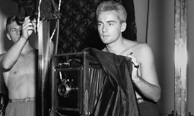 Black and White Photo of George Platt Lynes taking a photo topless as another man takes a picture of him, also topless.
