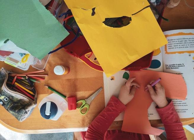 A photo of a child doing crafts with paper and other materials on a table