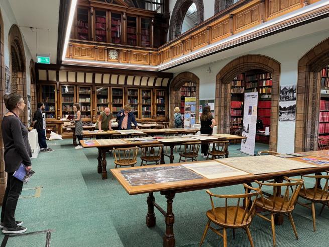 Image of interior of a library with lots of long tables filled with maps and prints.