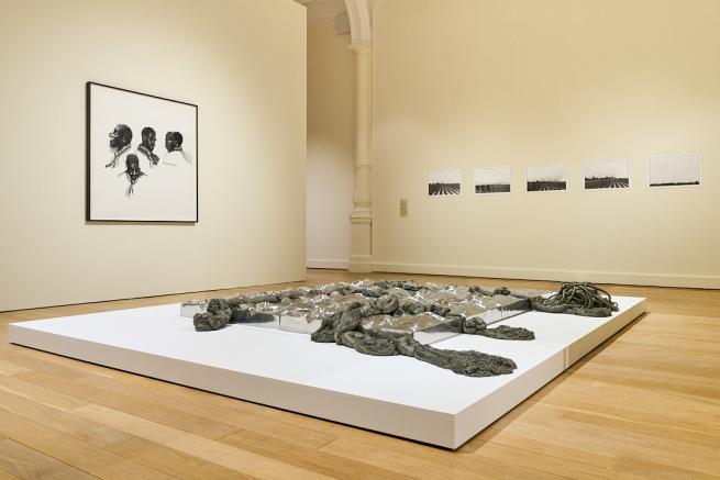 A photo of a sculpture and some paintings from the To Improvise a Mountain exhibition