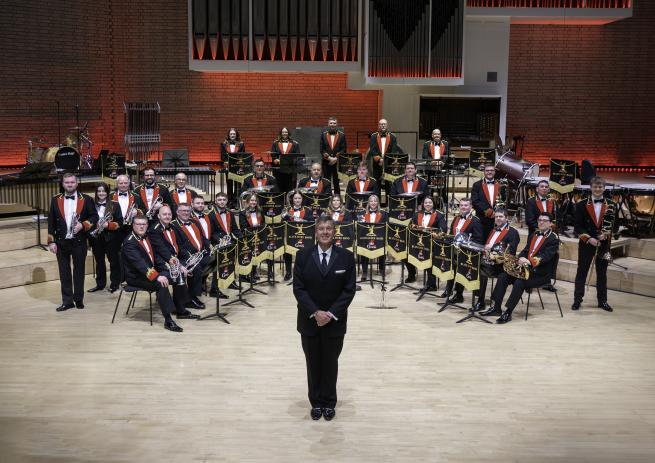 A brass band sat down on a stage ready to perform. 