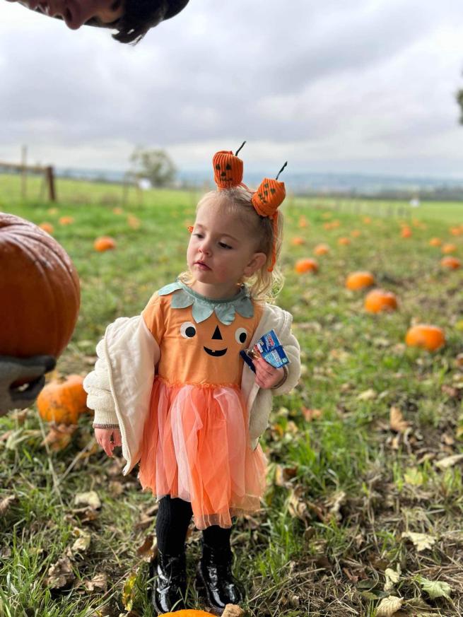 Girl wearing a pumpkin outfit in the pumpkin patch 