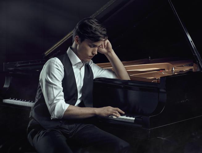 A musician sat at the piano deep in thought. 
