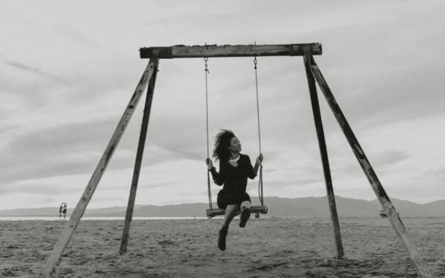 The album cover of Letters from a Black Widow showing Judith Hill on a beach, sitting on a swing