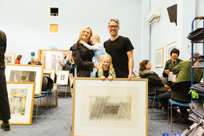 A couple and a child stood with their picture library print in Leeds Art Gallery