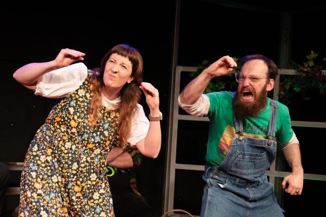 Two people stand on a stage, with crab styled hands, looking into the distance.