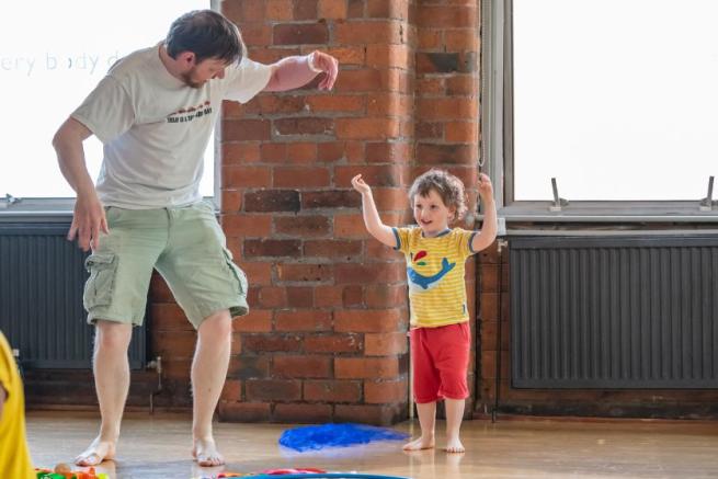 An adult and child dancing playfully together.