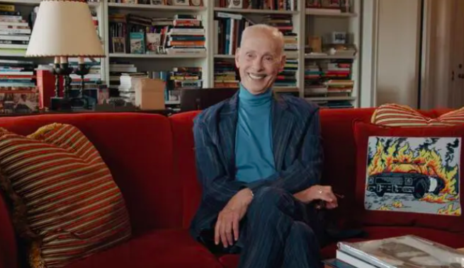 Image of John Waters sitting on a sofa from a still from the film Scala!!! 