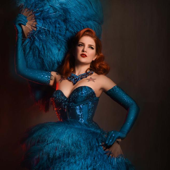 Burlesgue performer in a blue dress with a blue fan