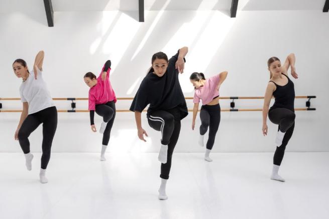 Five dancers with a knee and elbow raised