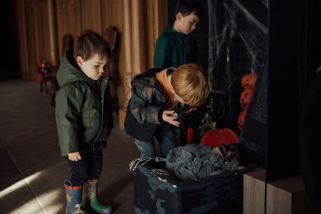 Photograph of children by a fireplace decorated with halloween pumpkins
