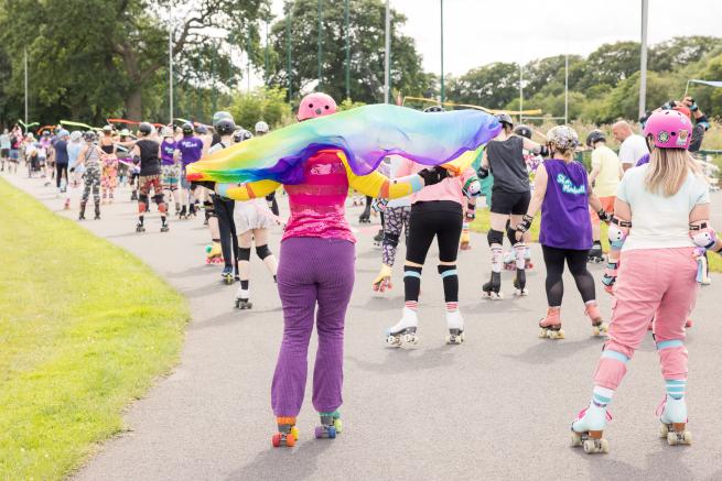 Skaters in colourful clothes skate outside on a cycle track