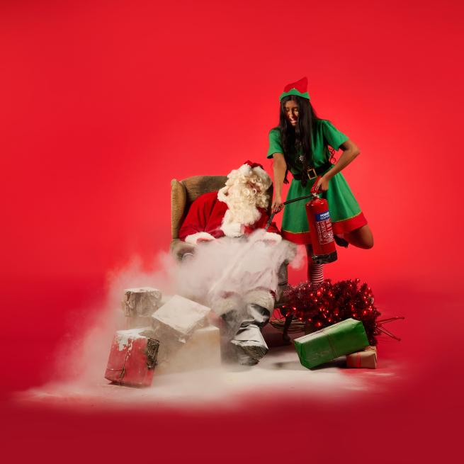 An elf firing a fire extinguisher at Santa 