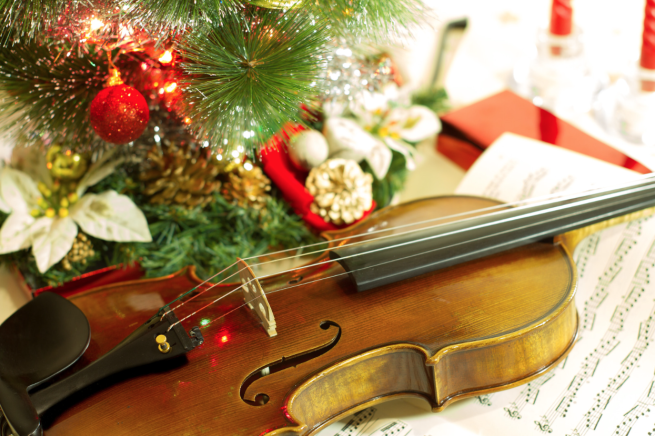 A violin surrounded by Christmas lights and decorations