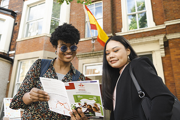 Two students looking at the Instituto Cervantes Leeds programme, standing outside the institute's building