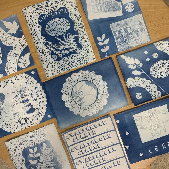 A flat lay of an assortments of cyanotype prints, blue and white in colour.