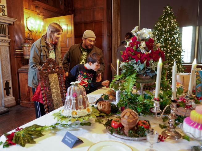 A group of people admiring a festive feast display in the Dining Room of Temple Newsam